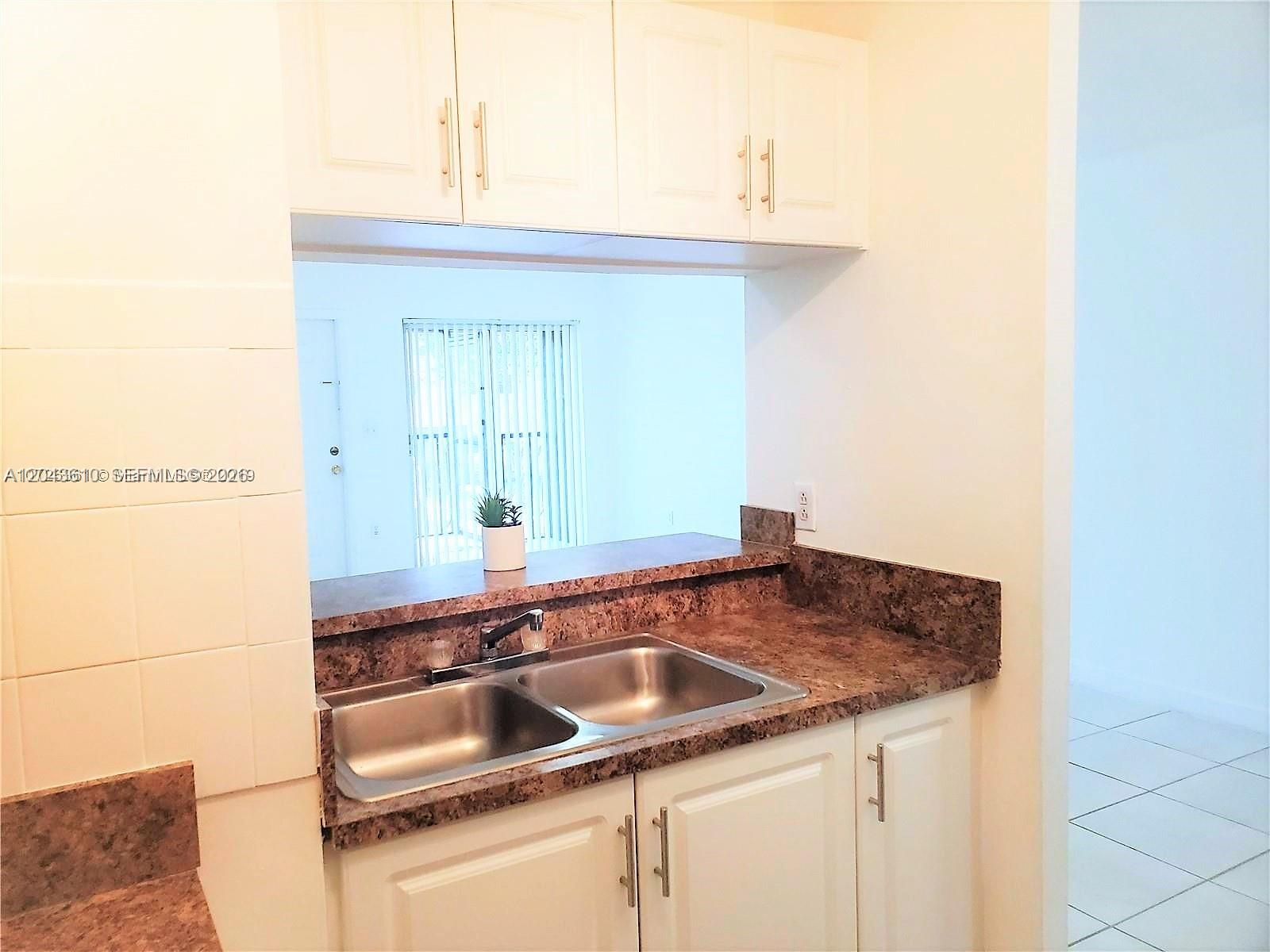 A kitchen features white cabinets, a double-basin sink, and a brown laminate countertop — 15659 SW 73rd Cir Ter # 4, Miami FL 33193, MIAMI, FL