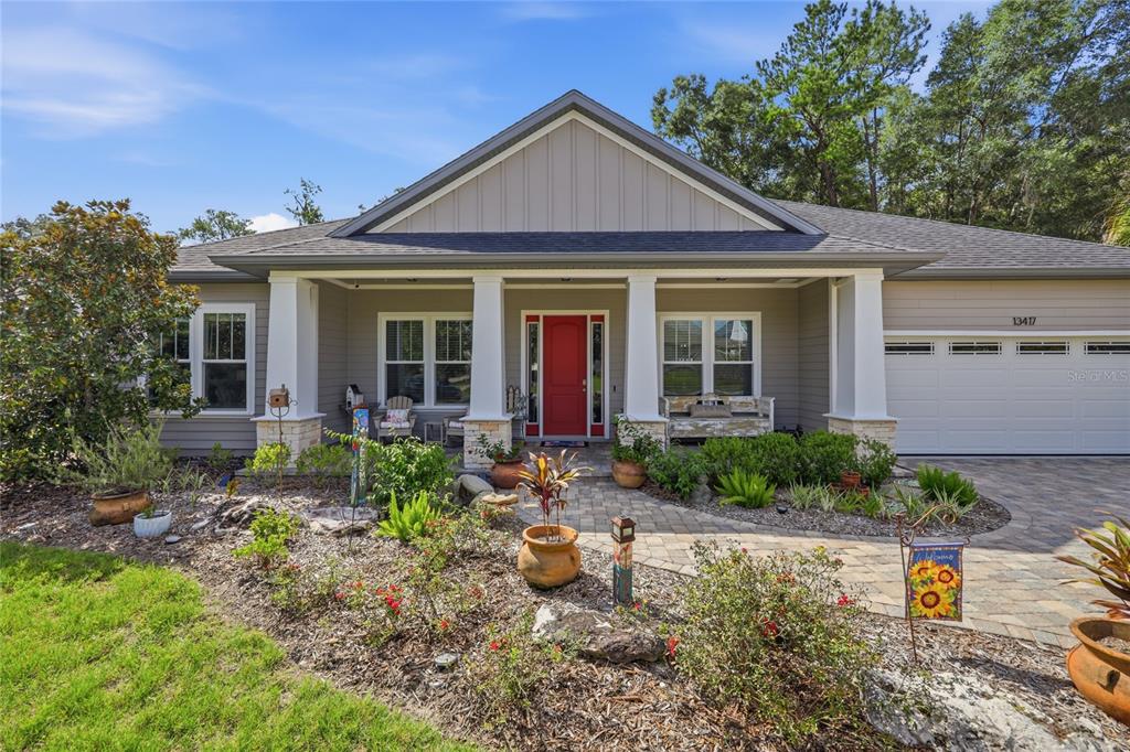 A single-story house with a gray exterior, white columns, a red front door, and landscaping — 13417 NW 10TH LANE, NEWBERRY, FL