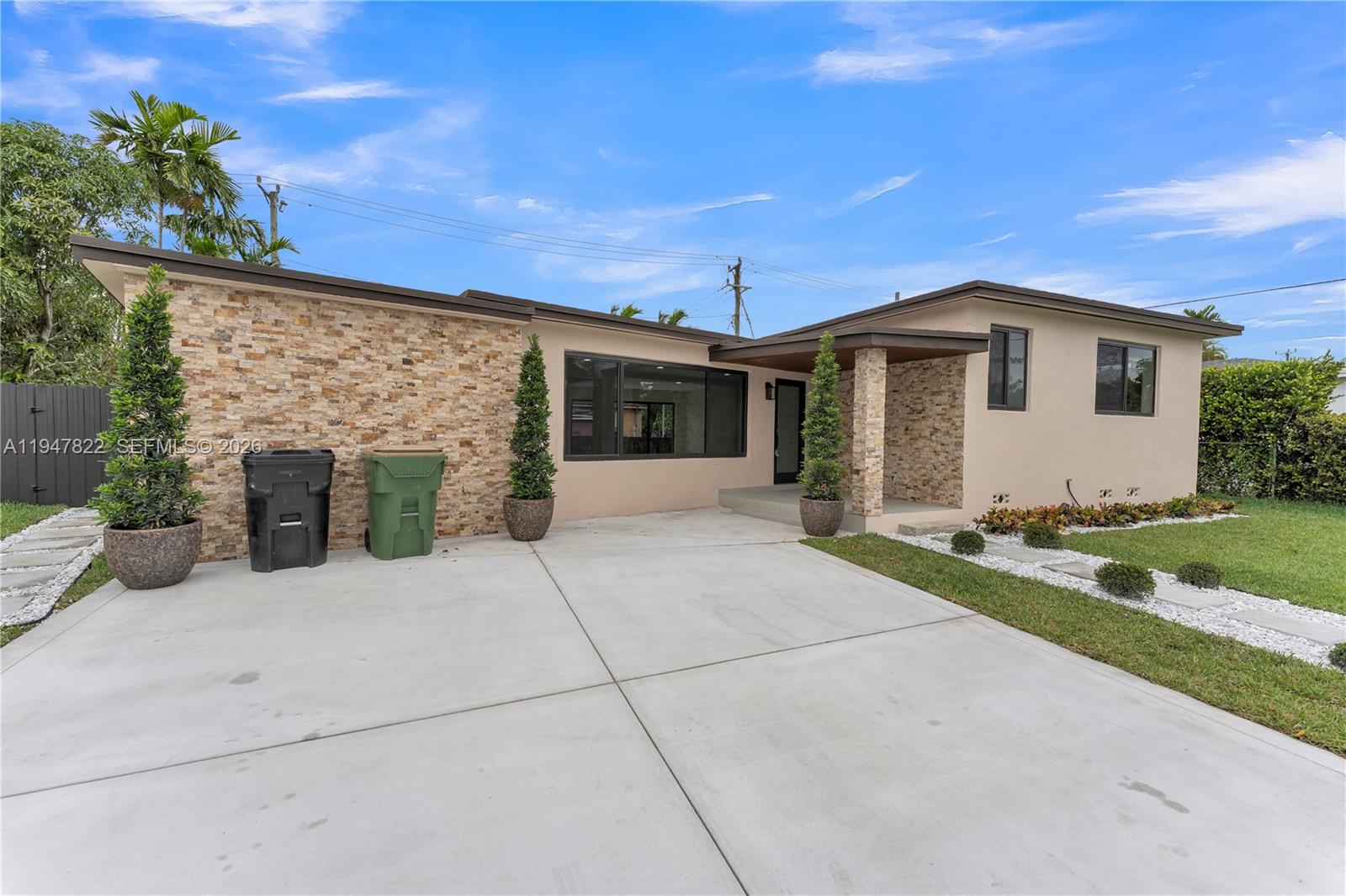 A single-story house features a stone facade, a concrete driveway, and a covered entryway — 141 NE 122nd St, North Miami FL 33161, NORTH MIAMI, FL
