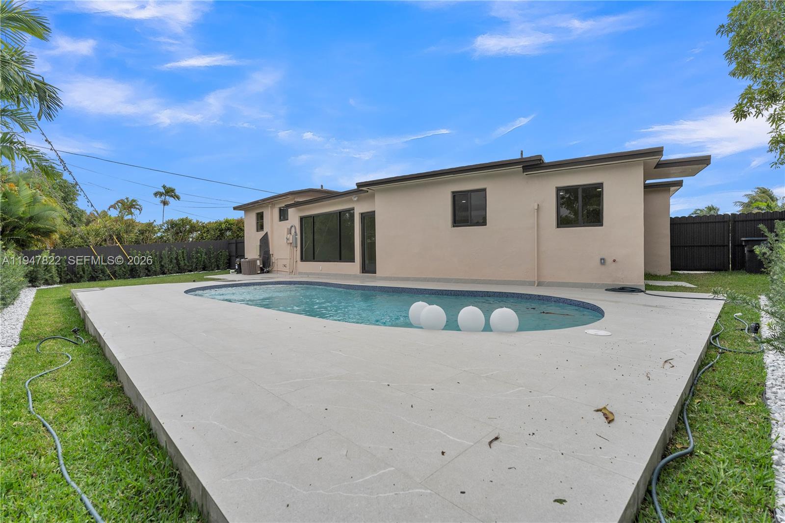 A backyard features a swimming pool with floating lights and a light-colored concrete patio — 141 NE 122nd St, North Miami FL 33161, NORTH MIAMI, FL