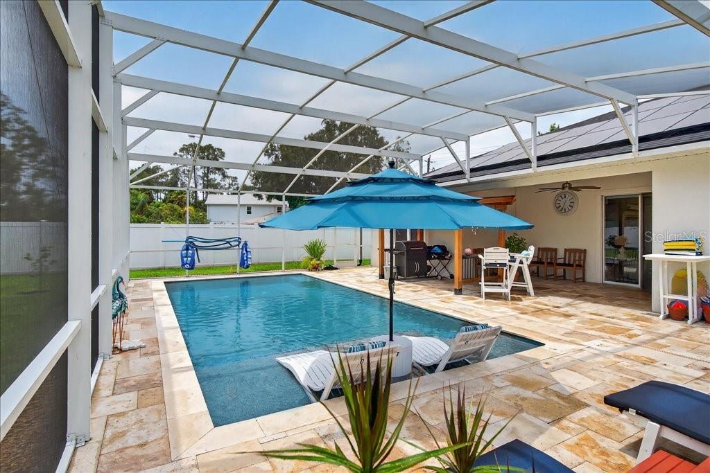 A screened-in patio features a swimming pool, lounge chairs, and a blue patio umbrella — 44 BOULDER ROCK DRIVE, PALM COAST, FL