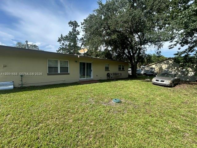 The rear exterior of a single-story house features a lawn, a sliding door, and a car — 399 BETH DR, Sanford FL 32771, SANFORD, FL