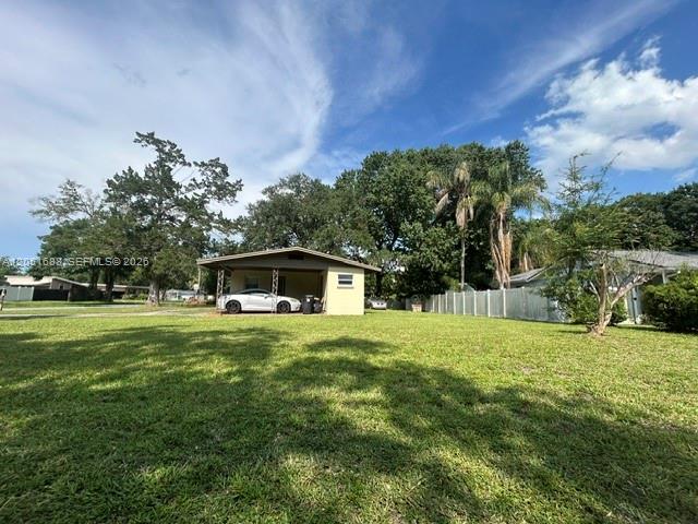 A single-story house with a carport sits on a large, grassy lot with trees — 399 BETH DR, Sanford FL 32771, SANFORD, FL