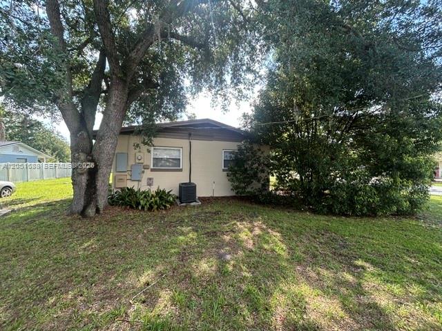 A tan, single-story house exterior is surrounded by large trees and a grassy lawn — 399 BETH DR, Sanford FL 32771, SANFORD, FL