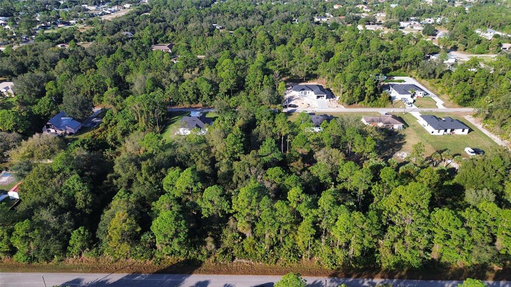 An aerial view shows several houses surrounded by dense trees and a paved road — 415 NORTH AVENUE, LEHIGH ACRES, FL