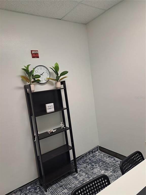 A small office space features a dark wood ladder shelf, a wall clock, and patterned flooring — 7345 W SAND LAKE ROAD UNIT 316, ORLANDO, FL