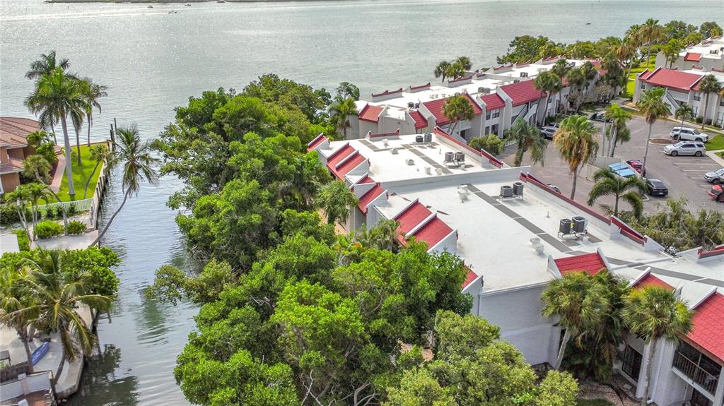 An aerial view shows a multi-unit residential building with red roofs near a waterway — 1801 GULF DRIVE N UNIT 248, BRADENTON BEACH, FL