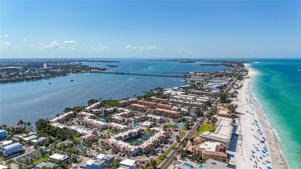 An aerial view shows a coastal resort area with multi-story buildings, a long bridge, and beach — 1801 GULF DRIVE N UNIT 248, BRADENTON BEACH, FL