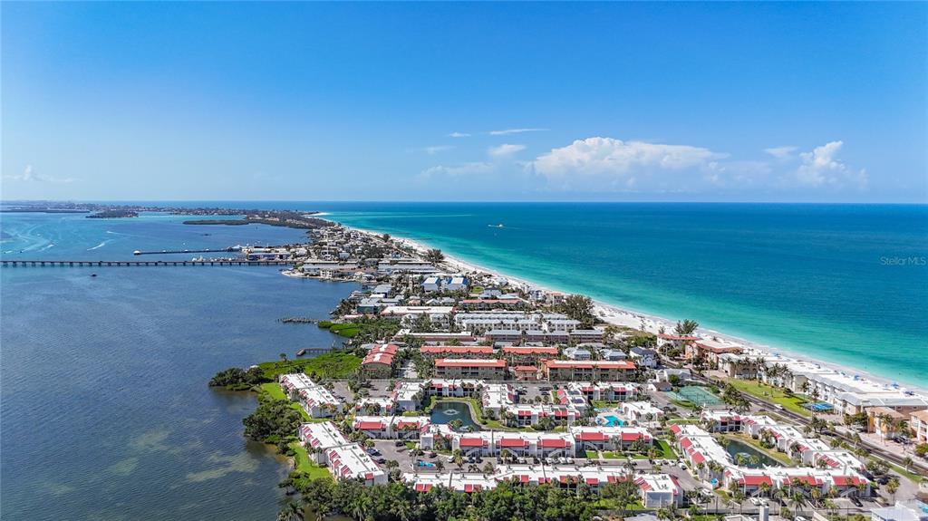 An aerial view shows a coastal resort complex situated between a bay and the ocean — 1801 GULF DRIVE N UNIT 248, BRADENTON BEACH, FL