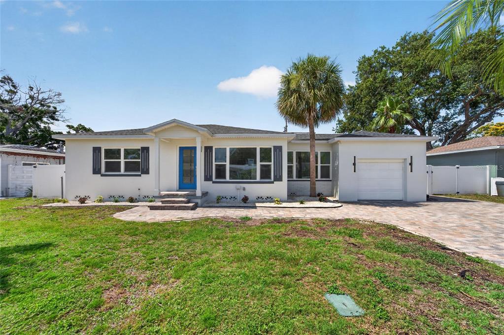 A single-story house with a blue front door, white exterior, and a paved driveway — 4810 DEL RIO WAY S, GULFPORT, FL