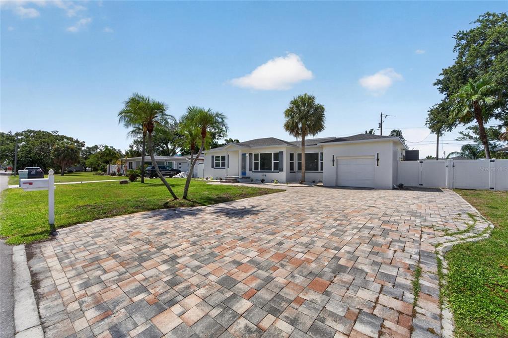 A single-story house with a paved driveway, white exterior, and palm trees in the front yard — 4810 DEL RIO WAY S, GULFPORT, FL