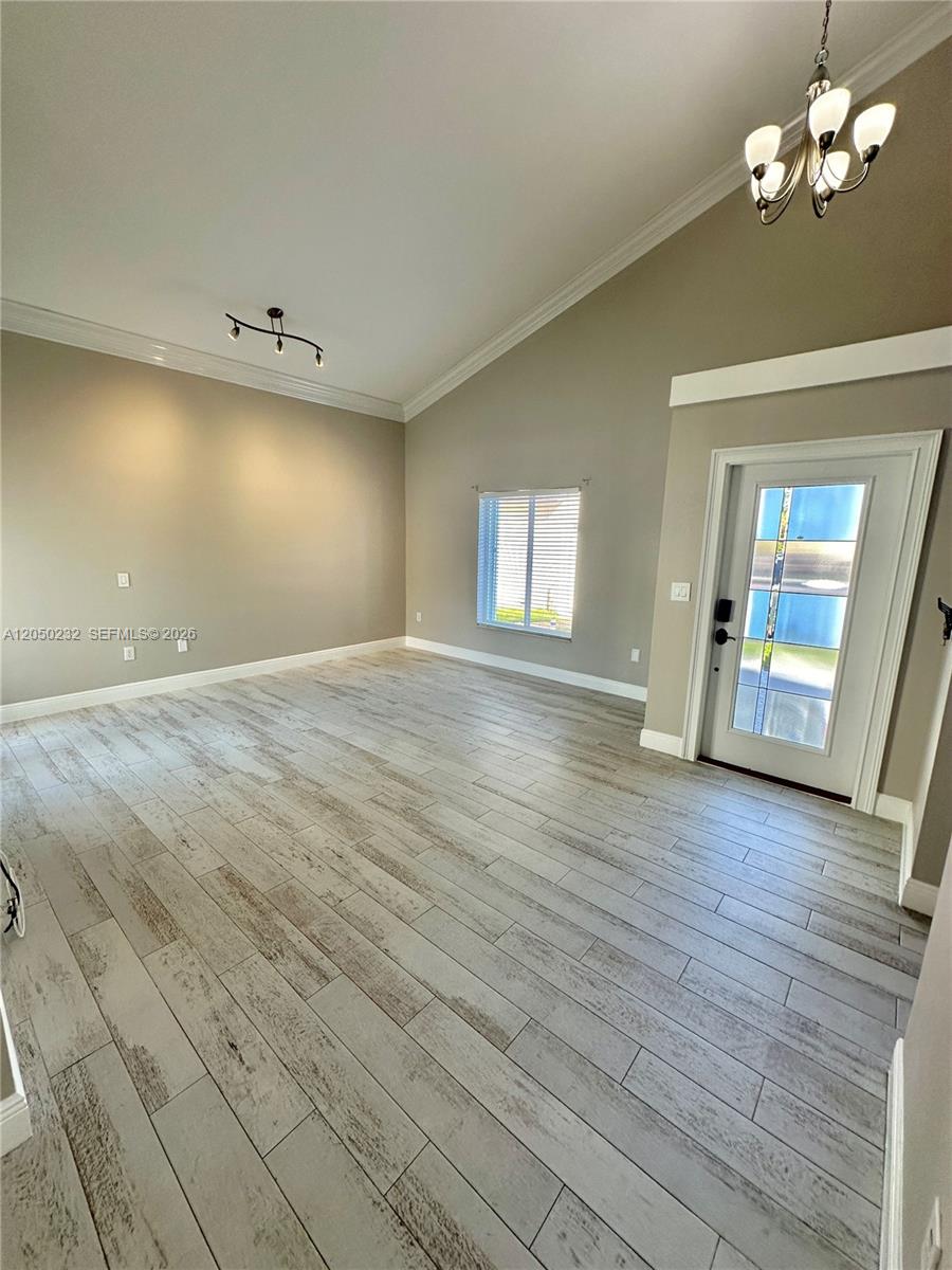 A living room features light-colored wood-look tile flooring, vaulted ceilings, and a front entry door — 19853 NW 64th Pl, Hialeah FL 33015, HIALEAH, FL