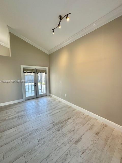 An empty room features light-colored wood-look tile flooring, beige walls, and a glass-paned double door — 19853 NW 64th Pl, Hialeah FL 33015, HIALEAH, FL