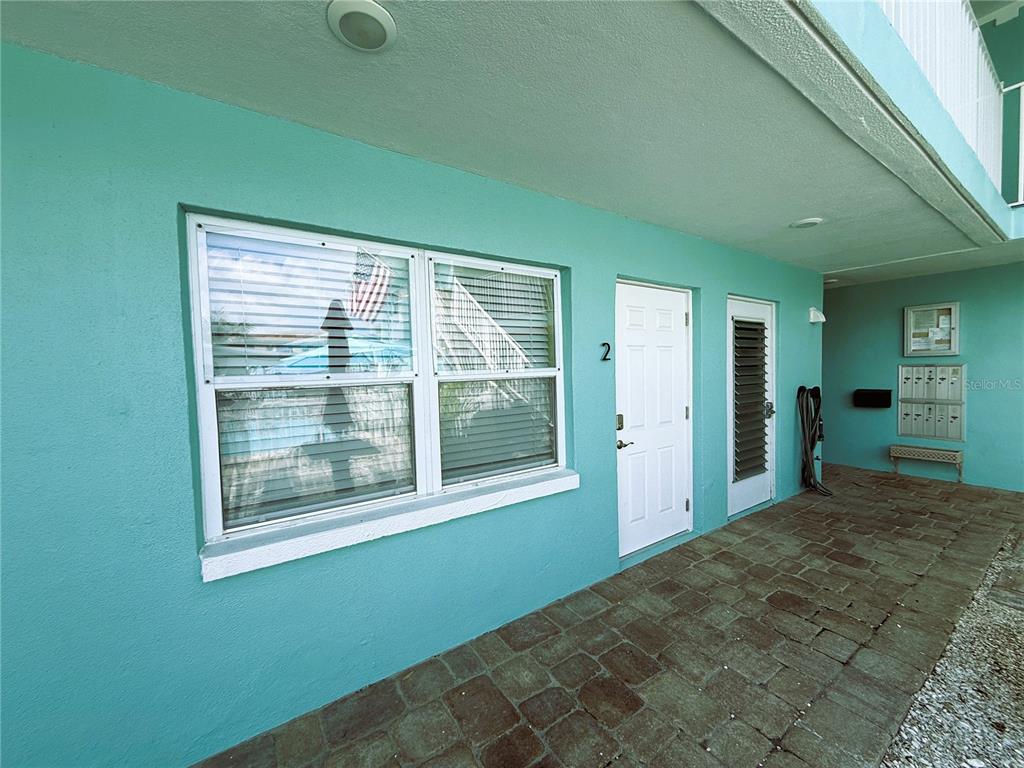 A teal exterior wall features a window, a white door labeled number two, and pavers — 11440 1ST STREET E UNIT 2, TREASURE ISLAND, FL