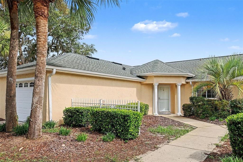 A single-story house with a tan stucco exterior, a white garage door, and a front entryway — 13646 SW 115TH AVENUE, DUNNELLON, FL