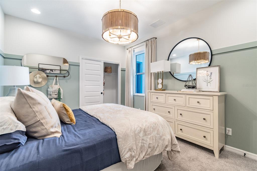 A bedroom features a blue bed, a white dresser, and sage green wainscoting — 1649 ROYAL COURT, PORT CHARLOTTE, FL