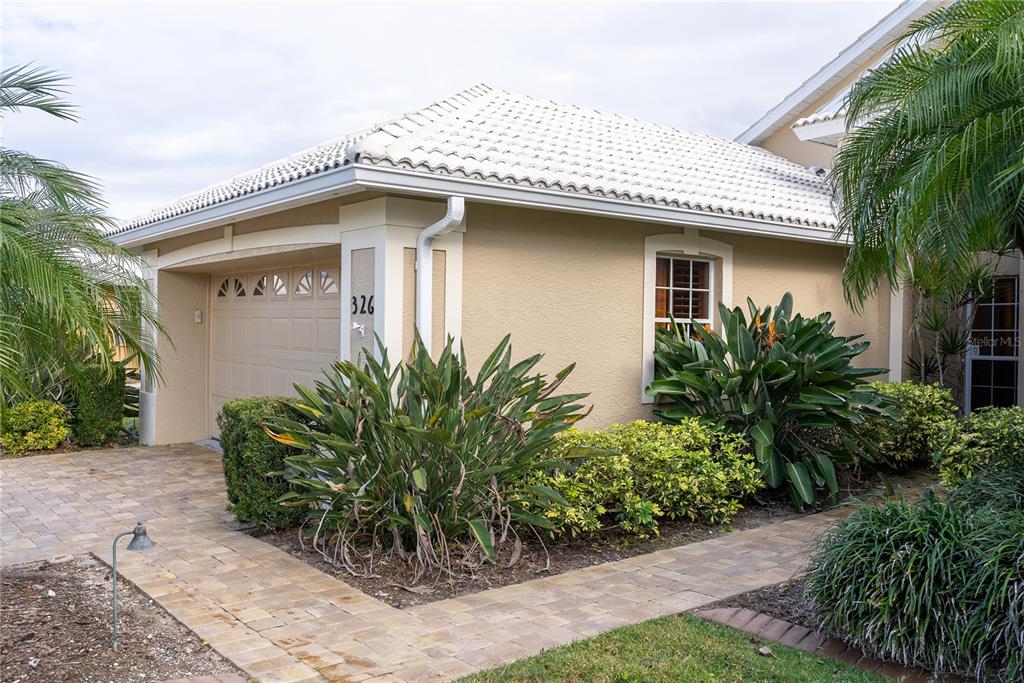 A tan house with a white tiled roof, a garage, and a paved walkway — 326 SAINT GEORGE COURT UNIT 14, VENICE, FL