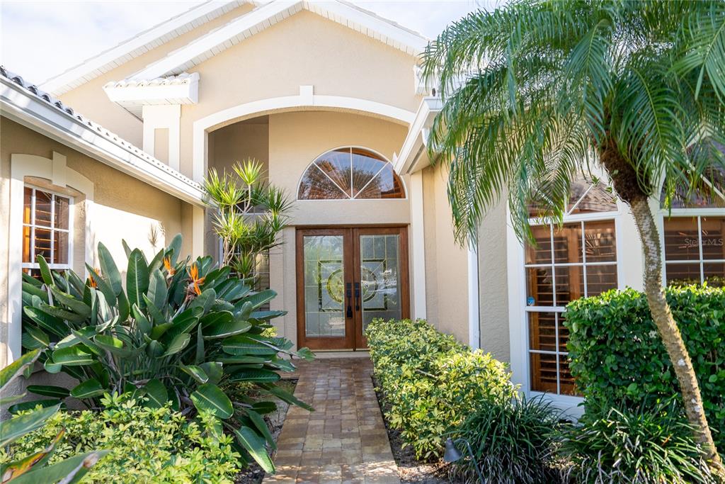 The exterior of a house features a stone walkway leading to double glass front doors — 326 SAINT GEORGE COURT UNIT 14, VENICE, FL