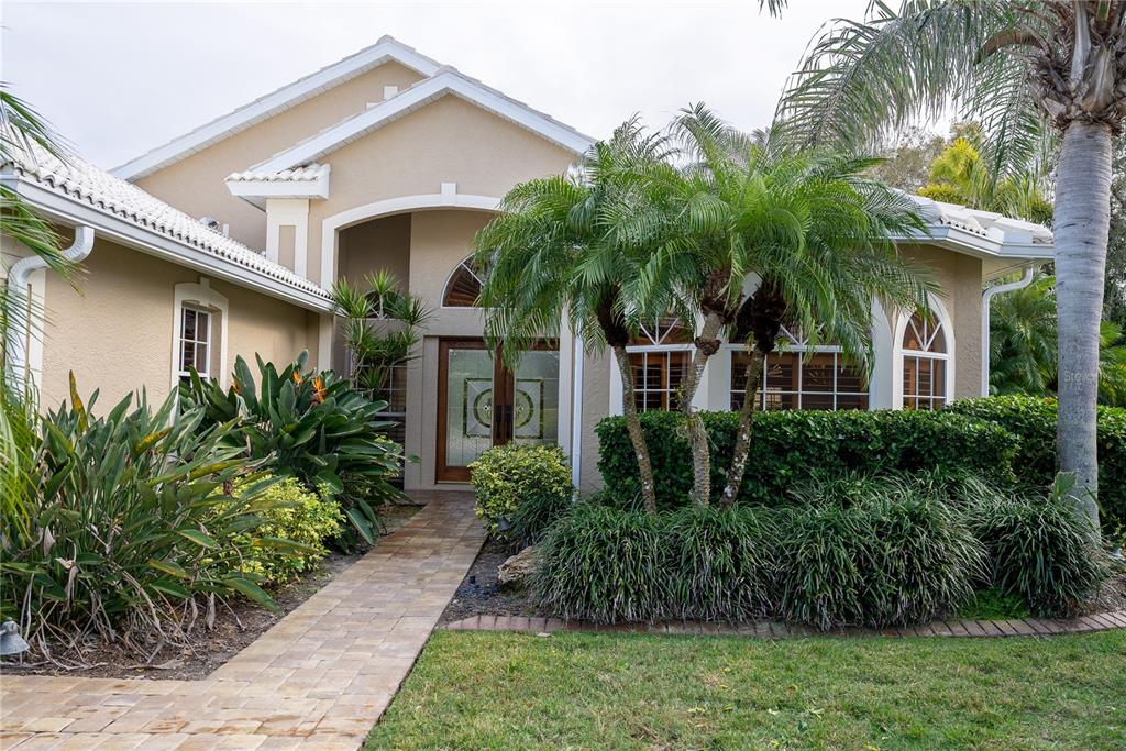 A beige house exterior features a paved walkway, a palm tree, and a glass front door — 326 SAINT GEORGE COURT UNIT 14, VENICE, FL