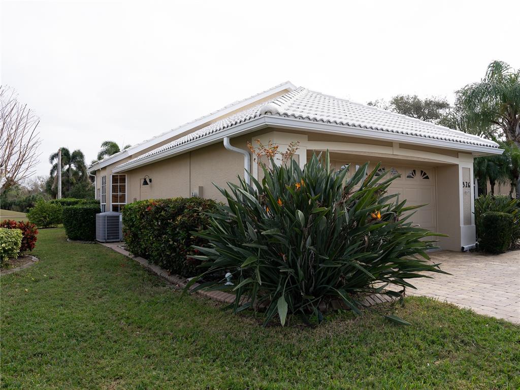 A side view of a beige house with a white tile roof and a garage — 326 SAINT GEORGE COURT UNIT 14, VENICE, FL