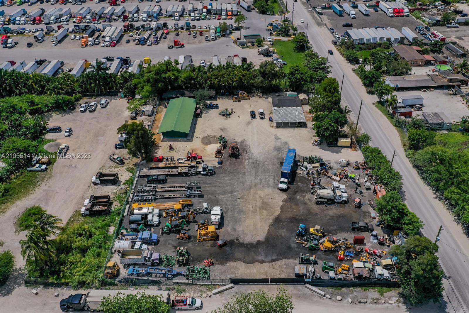 An aerial view shows a commercial lot with various trucks, trailers, and heavy construction equipment — 15721 NW 122 AVE, Miami FL 33018, MIAMI, FL
