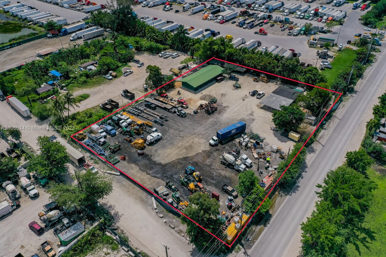 An aerial view shows a fenced industrial lot containing various trucks, construction equipment, and buildings — 15721 NW 122 AVE, Miami FL 33018, MIAMI, FL