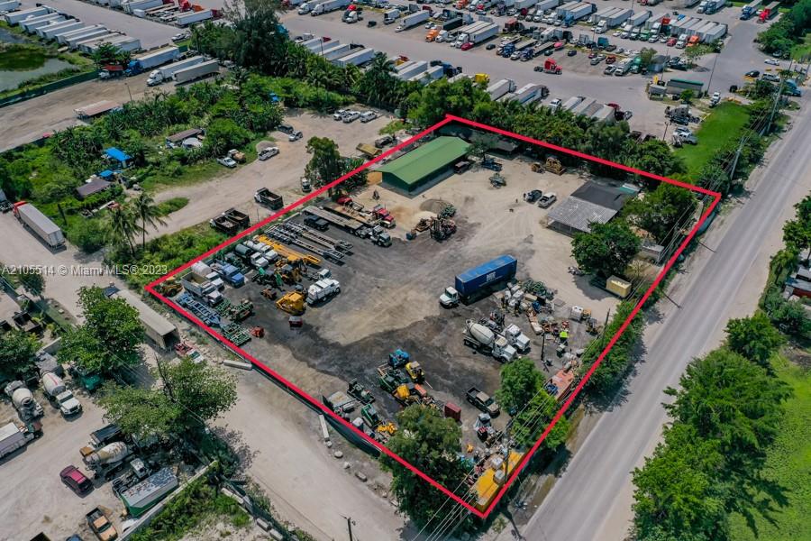 An aerial view shows a fenced industrial lot containing various trucks, construction equipment, and buildings — 15721 NW 122 AVE, Miami FL 33018, MIAMI, FL