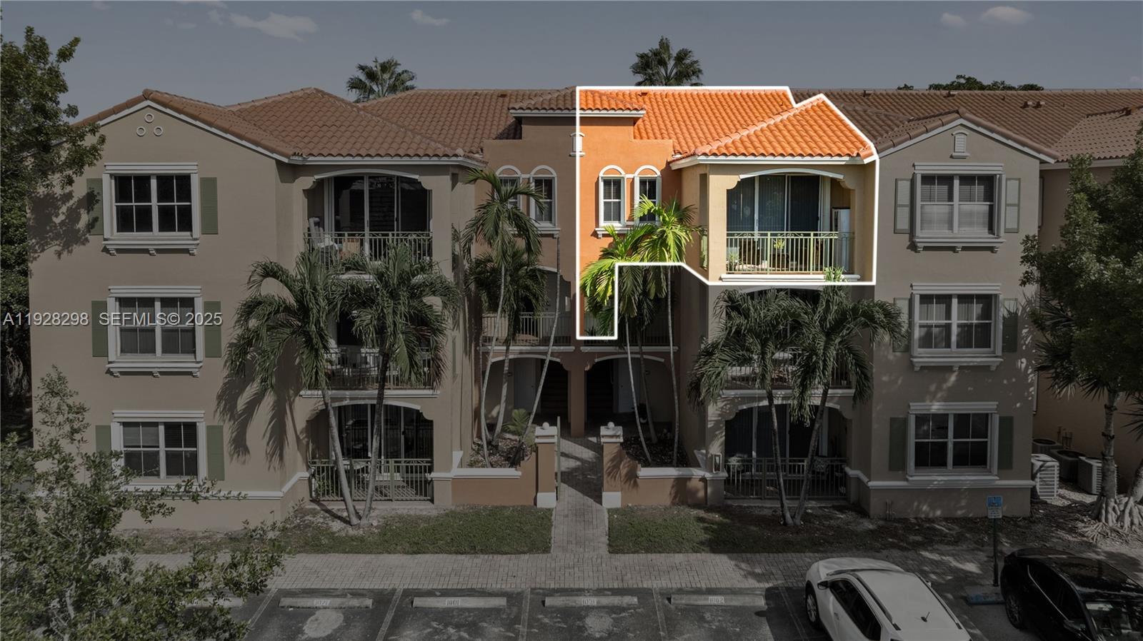 An exterior view of a multi-story apartment building with a highlighted top-floor balcony unit — 6500 NW 114th Ave # 1032, Doral FL 33178, DORAL, FL