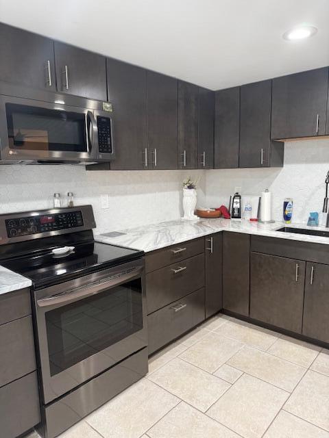 A kitchen features dark wood cabinets, stainless steel appliances, and white marble-patterned countertops — 99 Capri C # 99, Delray Beach FL 33484, DELRAY BEACH, FL
