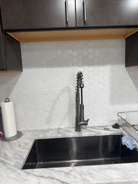 A kitchen sink area features a dark faucet, white hexagonal tile backsplash, and marble countertops — 99 Capri C # 99, Delray Beach FL 33484, DELRAY BEACH, FL