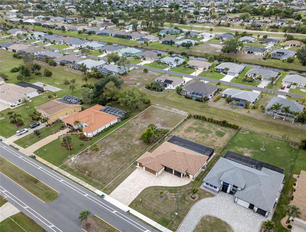 An aerial view shows a residential street with several houses and two vacant lots — 211 ROTONDA BOULEVARD N, ROTONDA WEST, FL