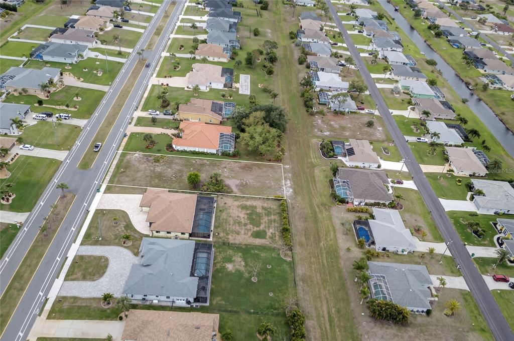 An aerial view shows a vacant residential lot situated between two existing houses — 211 ROTONDA BOULEVARD N, ROTONDA WEST, FL