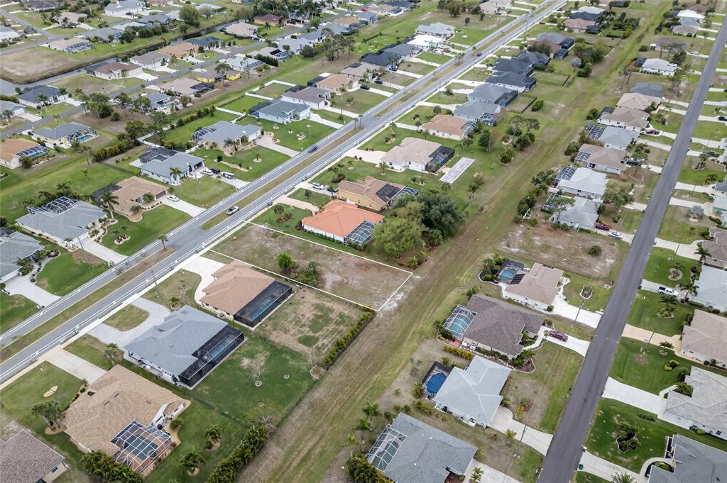 An aerial view shows a residential neighborhood with houses, streets, and a vacant lot — 211 ROTONDA BOULEVARD N, ROTONDA WEST, FL