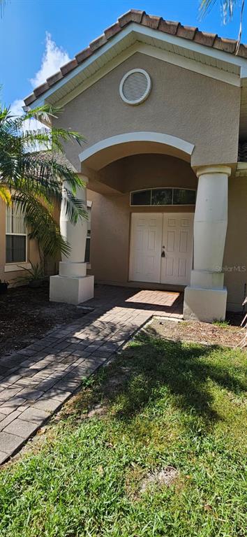 The exterior of a house features a covered entryway with two large columns and double doors — 3905 BOWFIN TRAIL, KISSIMMEE, FL