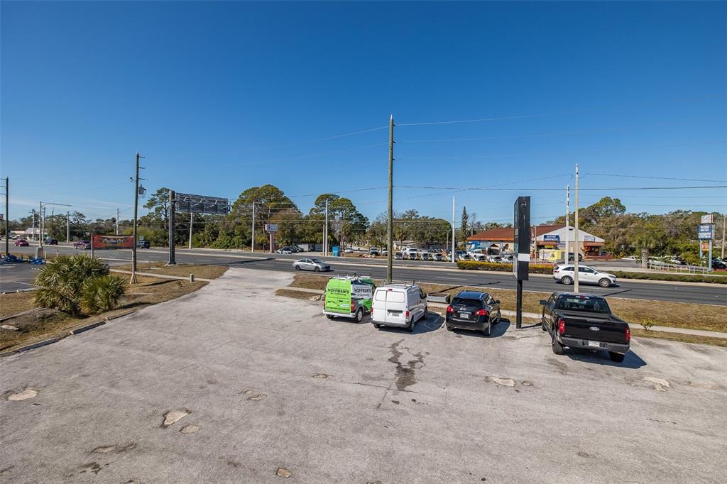 A paved parking lot with four vehicles sits in front of a multi-lane road — 8312 US HIGHWAY 19, PORT RICHEY, FL