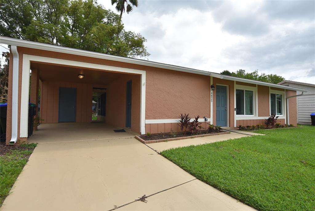 A single-story house with a tan stucco exterior, a carport, and a blue front door — 4825 LORETTA LANE, ORLANDO, FL