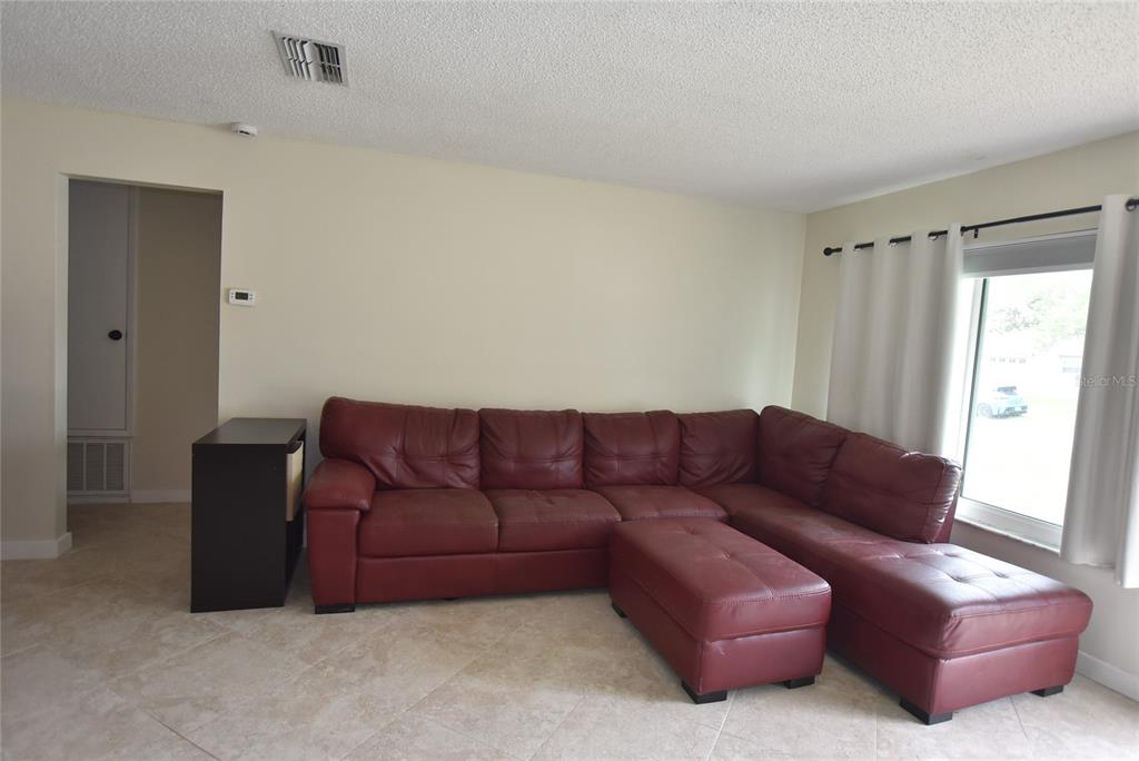 A living room features a large red sectional sofa on a light-colored tiled floor — 4825 LORETTA LANE, ORLANDO, FL