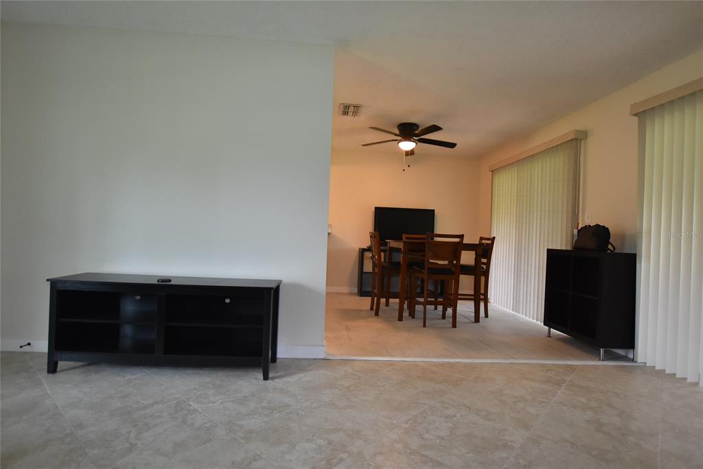 A living area with tile floors leads into a dining room with a ceiling fan — 4825 LORETTA LANE, ORLANDO, FL