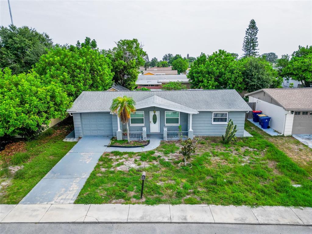An exterior view of a single-story gray house with a front porch and concrete driveway — 3049 KILBURN ROAD, HOLIDAY, FL