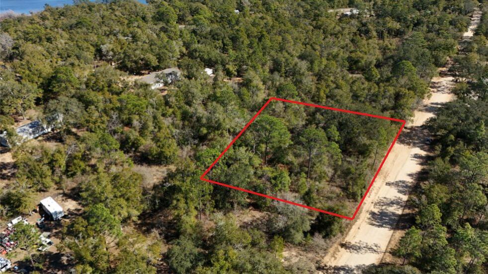 An aerial view shows a wooded, rectangular plot of land outlined in red beside a road — 0 Stewart Lake Road, FL 32428, FL
