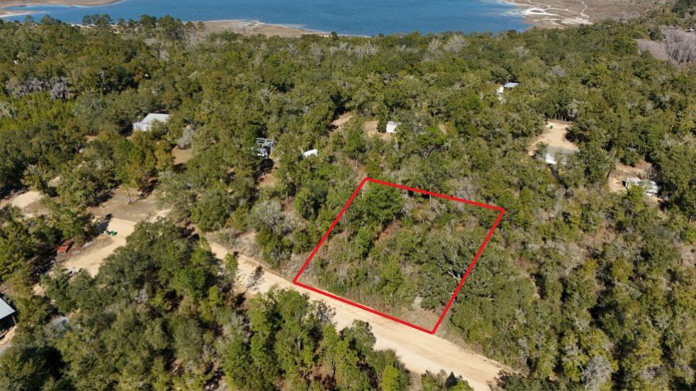 An aerial view shows a rectangular wooded lot outlined in red next to a dirt road — 0 Stewart Lake Road, FL 32428, FL