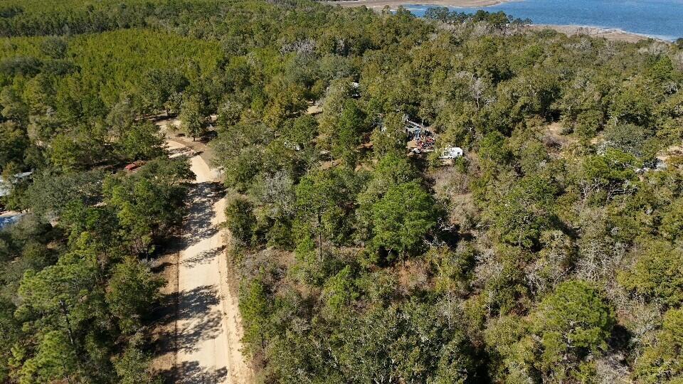 An aerial view shows a dirt road winding through a wooded area near a lake — 0 Stewart Lake Road, FL 32428, FL