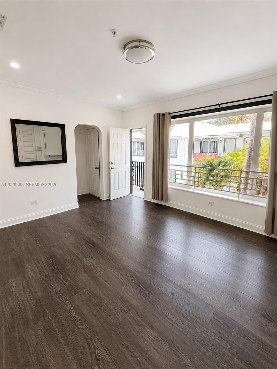 A living room features dark wood-look flooring, white walls, a large window, and a balcony door — 1536 Jefferson Ave # 4, Miami Beach FL 33139, MIAMI BEACH, FL