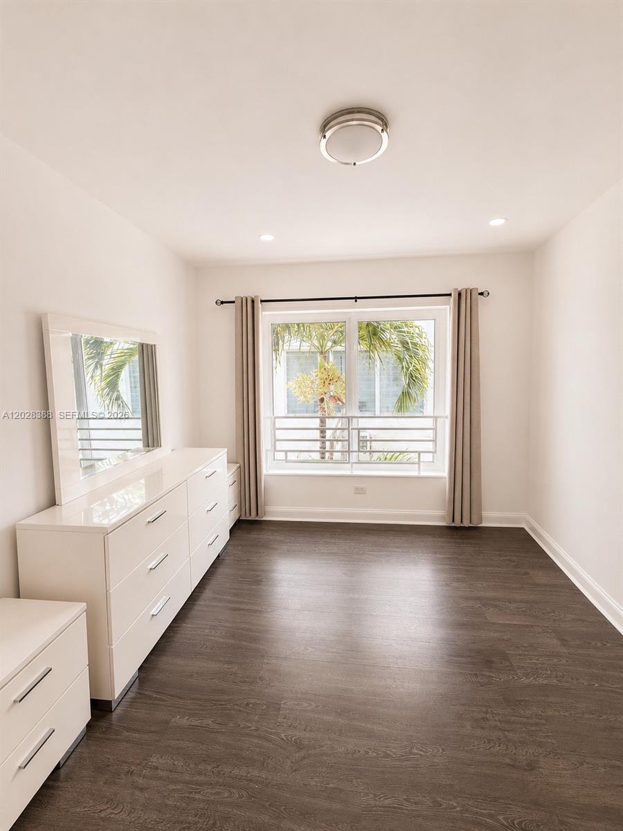 A bedroom features dark wood-look flooring, white walls, a white dresser, and a window — 1536 Jefferson Ave # 4, Miami Beach FL 33139, MIAMI BEACH, FL
