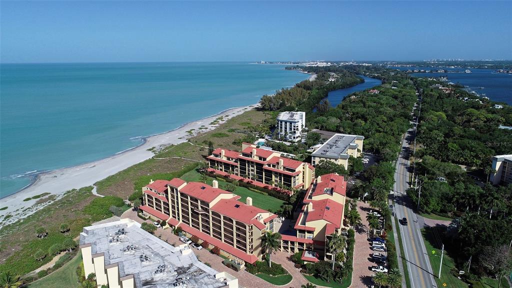 An aerial view of a beachfront condominium complex with a road running alongside the property — 8710 MIDNIGHT PASS ROAD UNIT 405, SARASOTA, FL