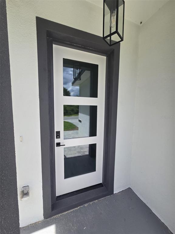 A white front door with three glass panels and black hardware sits in a dark frame — 4397 SW 169TH PLACE, OCALA, FL