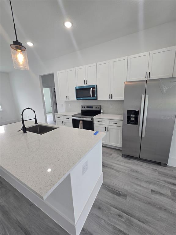 A modern kitchen features white cabinets, stainless steel appliances, and a quartz-topped island — 4397 SW 169TH PLACE, OCALA, FL