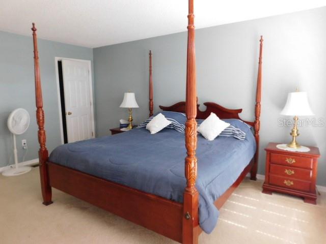 A bedroom features a wooden four-poster bed, two nightstands with lamps, and a floor fan — 2981 TOMORROW DRIVE, KISSIMMEE, FL