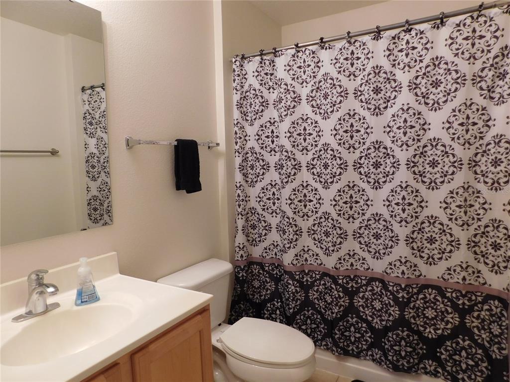 A bathroom features a vanity with a sink, a toilet, and a patterned shower curtain — 2981 TOMORROW DRIVE, KISSIMMEE, FL