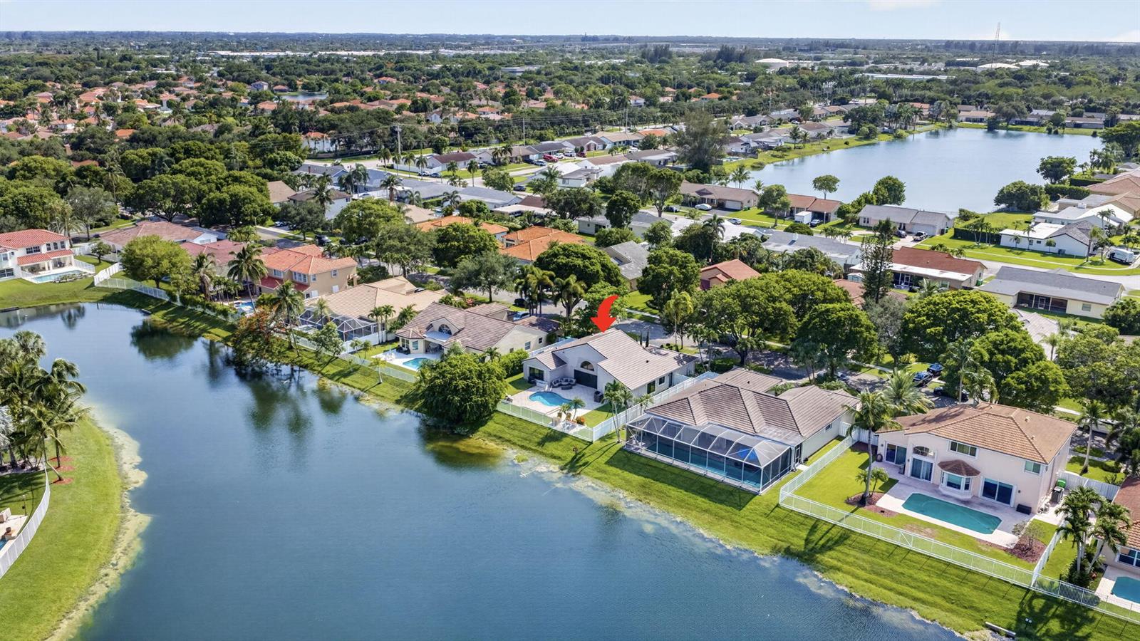 An aerial view of a suburban neighborhood featuring houses with pools along a lake — 912 NW 132nd Avenue, Sunrise FL 33325, SUNRISE, FL